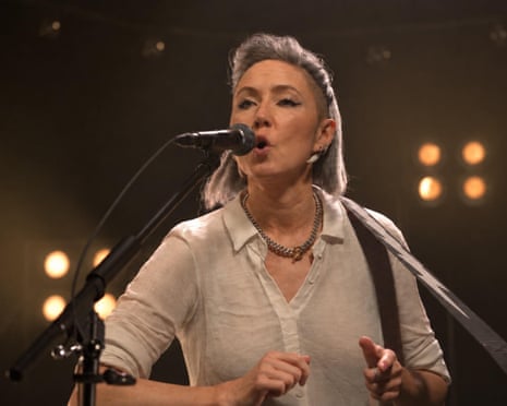 Musician KT Tunstall sings into microphone in dimly lit venue