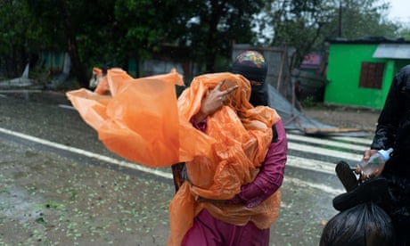 A woman holding her child walks towards a shelter as Cyclone Mocha takes hold. All photographs: Abir Abdullah