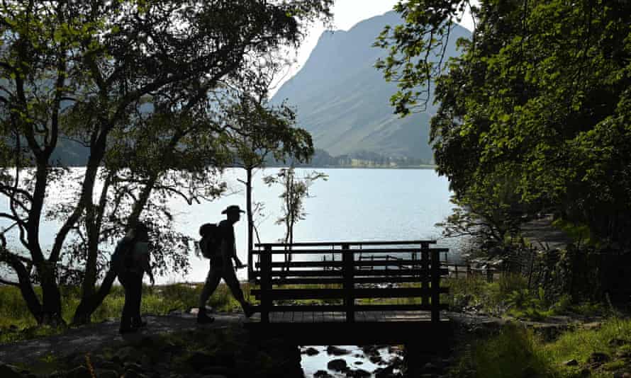 Walkers cross a footbridge beside Buttermere Lake.