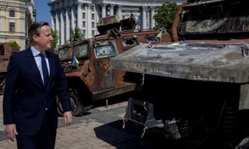 David Cameron looking at a burnt out vehicle in Ukraine
