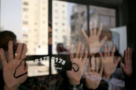 Women in Beirut display a face mask bearing a helpline number