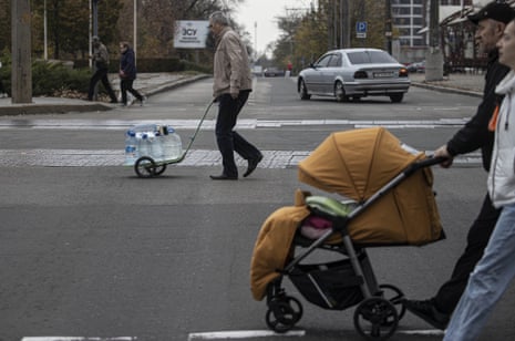 Ukrainian citizens carry bottles and buckets to receive clean water in Mykolaiv.