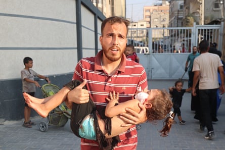 A Palestinian man carries a wounded girl