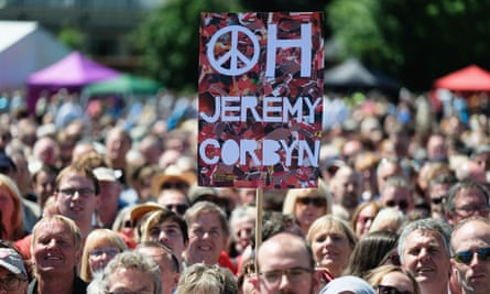 A Jeremy Corbyn placard is held above the heads of the crowd.