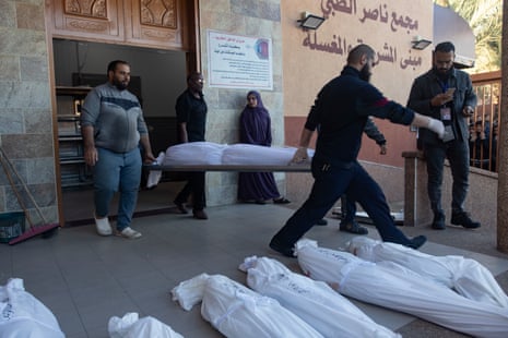 Morgue staff at Nasser hospital carry out the wrapped bodies of Abu Hatab family members, who were killed during an Israeli airstrike in the southern Gaza Strip.