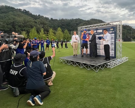 Broadcast media record a trophy presentation on a stage on the pitch