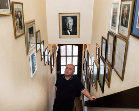 A photo of Andrew Broughton going up the stars, the walls on either side covered with framed autographs.