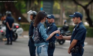 Kendall Jenner handing a bottle of Pepsi to a man in police uniform
