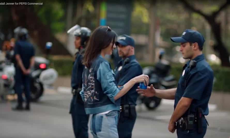 Kendall Jenner handing a bottle of Pepsi to a man in police uniform