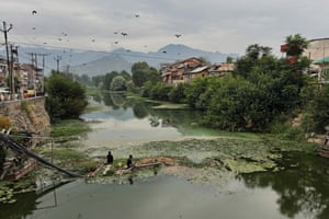 People fish in a polluted water canal