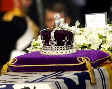 Crown encrusted with diamonds on a purple cushion.