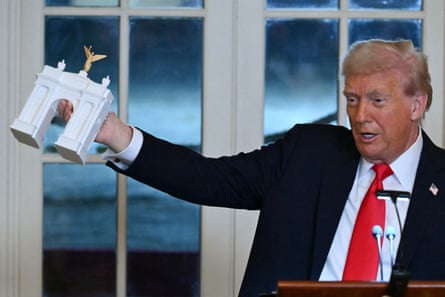 Trump holds up a model of an arch.