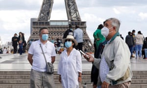 People wearing protective masks stand at the Trocadero square near the Eiffel Tower.