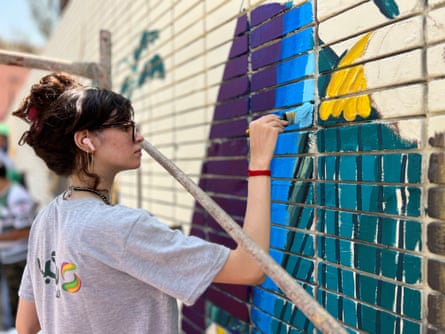 A woman paints on a wall