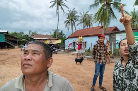 Cambodians outside a house pointing and looking to the sky