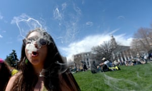 A woman blows smoke rings with marijuana smoke during a rally at the Civic Center in Denver, Colorado, last year.
