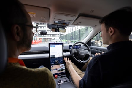 Steve Rose and Alex Kendall sit in a Wayve driverless car as it proceeds down a road in London. Kendall’s hands are not on the wheel