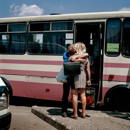 A man embraces a woman standing on the street by the door of a bus