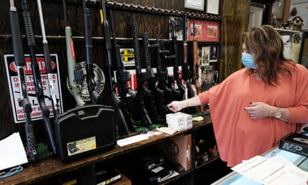A woman selling guns at a gun store.