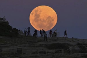 People watch as the moon rises over the Pacific ocean at Bondi Beach in Sydney, Australia