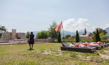 A large memorial bearing 46 names stands before a row of five tombs in the mountain village of Beleg, Kosovo