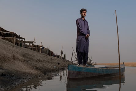 Bashir Ahmed in his boat on the lake, next to simple huts built on the raised banks of the Right Bank Outfall Drain.