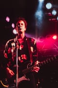 A man holding a bass and singing into a microphone with stage lights on him