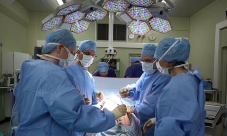 A surgeon and his theatre team perform surgery at the Queen Elizabeth hospital in Birmingham.