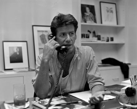 A black-and-white picture Calvin Klein sitting at a desk talking on the phone