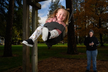 A little girl is pushed on a swing by her mom