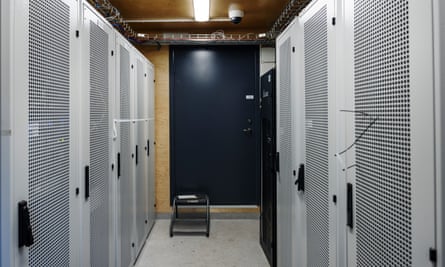 View inside the datacentre, with wiring running around at the edge of the ceiling above grey metal doors housing the computer systems