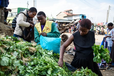Rebecca Awuor buys greens from a market stall and loads them into her reusable bag.