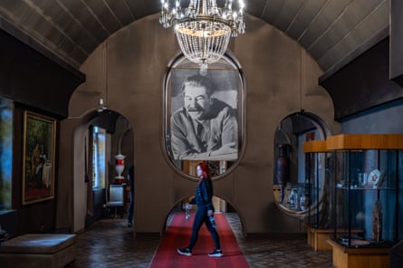 A tourist walks past a large portrait of Stalin under a chandelier in the museum