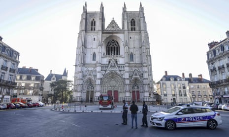 French police officers inspect the partially burnt facade of the Cathedral of St Peter and St Paul in Nantes, western France