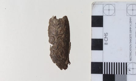 A piece of elaborately carved bone, once probably part of a medieval bow, now reduced to a broken fragment and discarded on the surface near a looted grave.