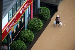 Overhead shot of a woman wading through a flooded street, carrying shopping bags