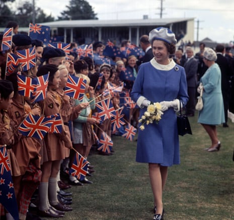 The Queen walks along a row of Brownies waving Union Jack and New Zealand flags