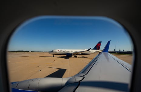A Delta plane taxis on the runway at Dulles Airport, viewed through a plane window