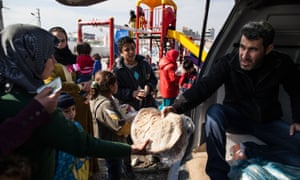 A woman receives a bread ration in a refugee camp for Syrians near the town of Akçakale and the Syrian border, Turkey.