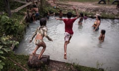 Two children jump into a small natural pool as others play in the water