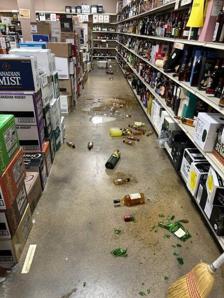 A store with broken liquor bottle littering the floor.;