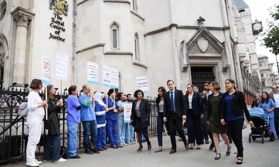 Doctors from Justice for Health walk past supporters outside the Royal Courts of Justice.