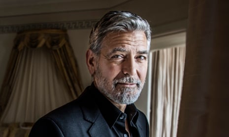 George Clooney in a dark suit looking to camera
