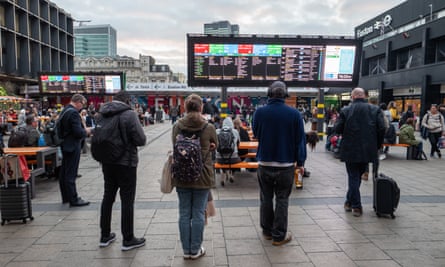 Commuters wait for their trains underneath the new information boards outside Euston rail station.