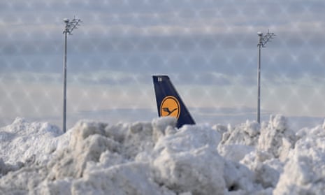 A tail fin of a Lufthansa plane is pictures behind snow at the terminal as Munich airport