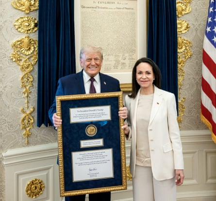 Donald Trump holding a framed prize standing next to Maria Corina Machado in the Oval Office