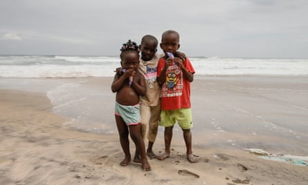 Three children eating wrapped ice-cream on a beach