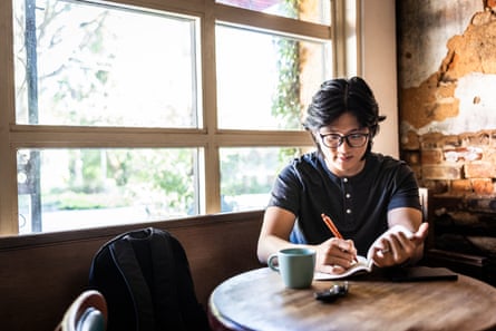 Young man writing in journal in cafe
