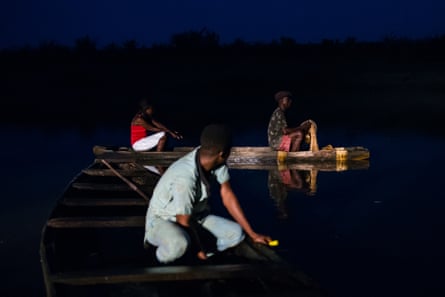 Three people in fishing canoes at night