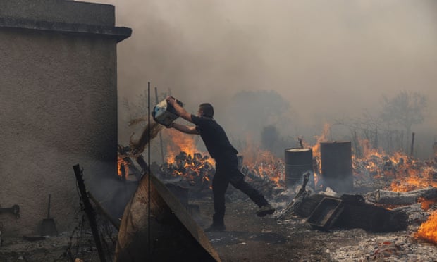 A police officer tries to extinguish the wildfire burning in the village of Vatera, Lesbos